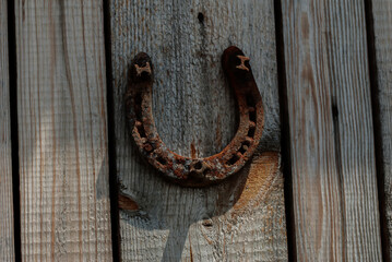 An old rusty metal horseshoe on a wooden house wall.