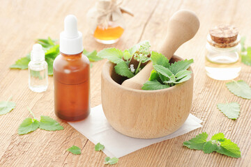 Lemon balm oil or extract  on wooden rustic table with fresh leaves and flowers nearby, copy space, herbal remedy for insomnia and stress, natural hair and skin treatment, aromatherapy concept