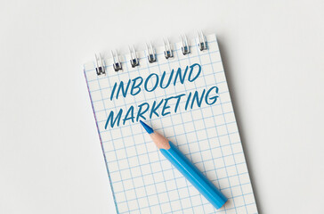 A blue pencil is on a blue and white notebook with the word Inbound Marketing written in blue