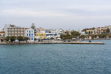 Aerial view of buildings with diverse architectural styles stand along the coastline, reflecting the city's charm and history, Tinos, Tinos, Greece.