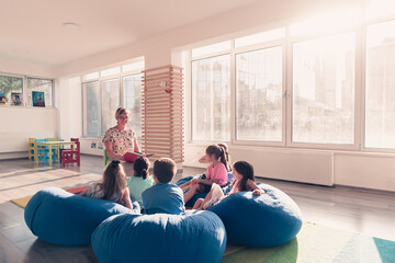 Reading time in elementary school or kindergarten, teacher reading a book to kids in elementary school or kindergaden. Selective focus