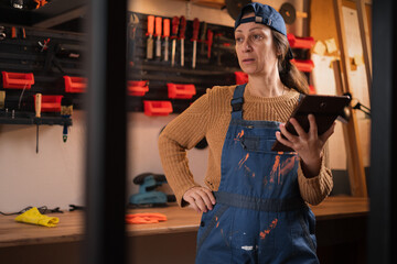 Woman repairman, craftsman or mechanic wearing overalls search for material, deal and discount on web using digital tablet in garage workshop