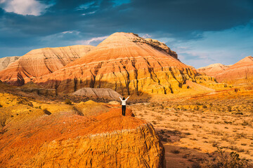 Colorful striped layered sedimentary mountain and tourist standing in Altyn Emel national park,...
