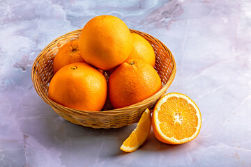 Fresh Oranges in a Wicker Basket on Marble Background