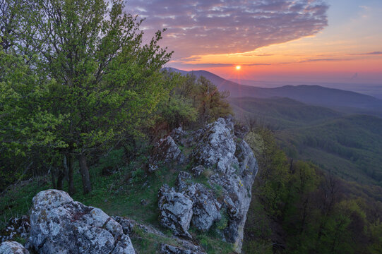Aerial view of Cierna Skala rock with its stark white cliffs contrasting with the vivid sunset, the sun a fiery orb against the soft pastel sky, Plavecky Mikulas, Bratislava Region, Slovakia.