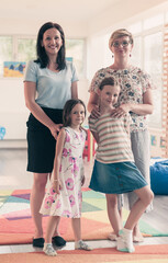 Portrait of a mother with her daughters in a modern preschool institution. Selective focus