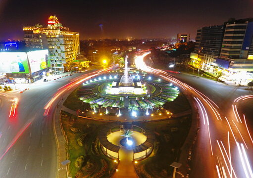 Aerial view of Liberty Market Gulberg III roundabout, a luminous vortex of light trails amidst Lahore's vibrant urban tapestry, Punjab, Pakistan.