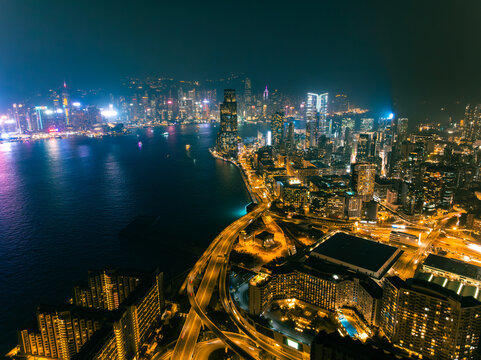Aerial view of the vibrant city lights shimmering against the dark harbor waters near the ICC Tower, Hong Kong, Hong Kong Island, Hong Kong.