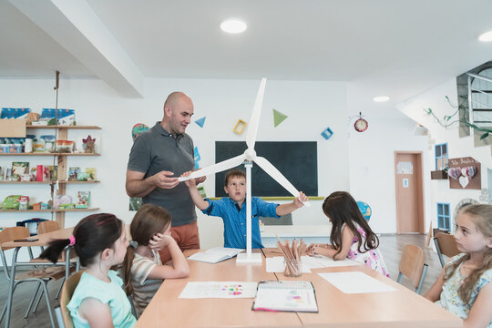 Elementary School Stem Robotics Classroom Diverse Group of Children Building and Programming windmill ecology robot concept. Together Talking and Working as a Team. Creative Robotics Engineering - Powered by Adobe