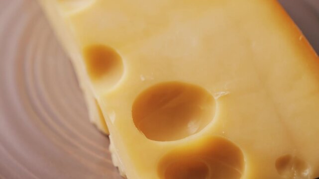 Bright yellow Emmental cheese or Maasdam cheese with large holes close up.