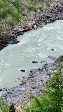 4K Vertical shot of Chenab river flowing in the Himalayan mountain valley as seen from the Killar Kishtvar highway in Himachal Pradesh, India. Scenic view of river flowing in the Himalayas.