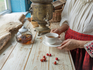 Woman is holding a cup of tea in a teapot