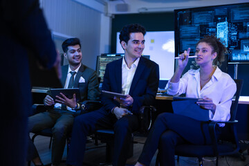 Team of diverse financial analysts and IT experts actively discussing an innovative business strategy at command center. Woman raises her hand to contribute a key idea regarding global market trends