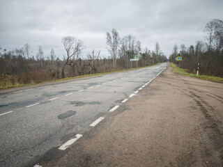 Road with a lot of potholes and a lot of trees in the background