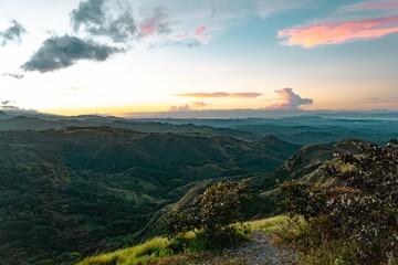Soft Pink and Orange Clouds over Green Tropical Slopes and Hiking Path