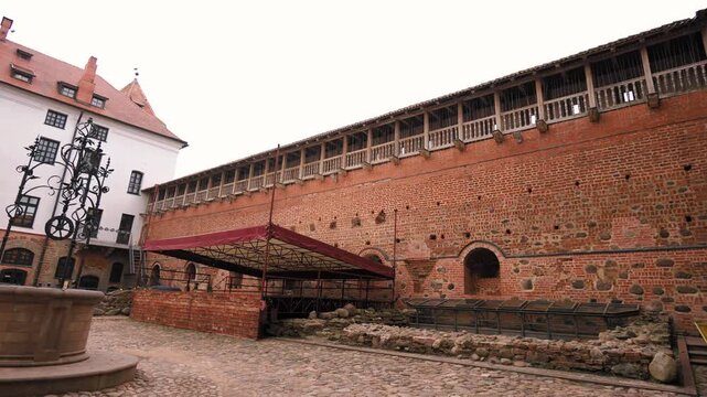 Tourists exploring the historic cobblestone courtyard of the mir castle complex, a unesco world heritage site in belarus, showcasing medieval gothic and renaissance architecture