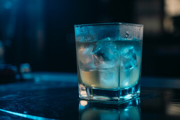 Refreshing blue cocktail on ice in a modern glass