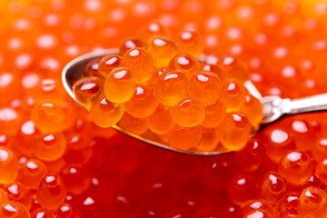 Red caviar.  Delicious red caviar in a silver spoon, closeup. Salmon fish roe macro shot. 