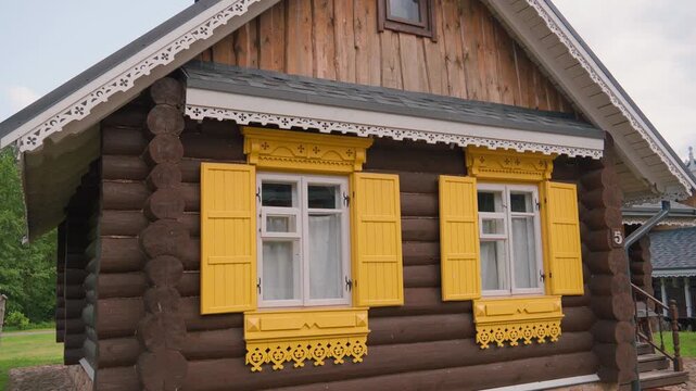 Beautiful old russian izba with intricately carved wooden window frames and bright yellow shutters, traditional slavic architecture and rustic village heritage exterior