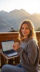 Digital nomad woman enjoying morning coffee on alpine balcony with laptop. Concept of workation, digital nomad lifestyle and work&ndash;life balance in nature.
