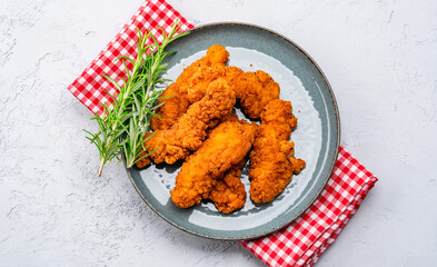 Fried chicken breast strips on grey table background. Delicious chicken crisps