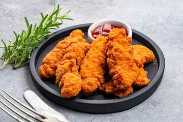 Fried chicken breast strips on grey table background. Delicious chicken crisps