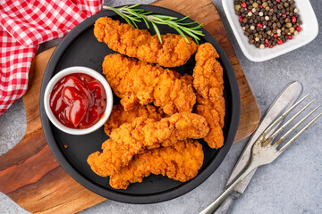 Fried chicken breast strips on grey table background. Delicious chicken crisps