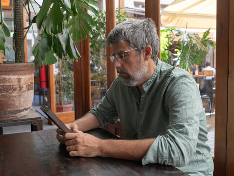 Man reading digital content on tablet in cafe - Powered by Adobe