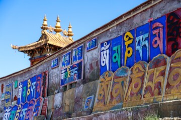 Colorful Tibetan script and sacred motifs decorate the Thousand Buddha rock carvings in Lhasa, Tibet, reflecting rich Buddhist heritage, spirituality, ancient art, and cultural tradition.