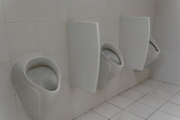 White ceramic urinal on tiled wall in public restroom. Minimalist restroom design with sleek urinal and sterile tiled surfaces in urban infrastructure