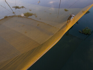 Aerial view of a fisherman on a traditional fishing net stretching across the water, Hoi An, Quang Nam, Vietnam.