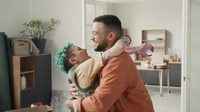 Happy girl with bionic arm jingling keys to new apartment, excited boyfriend lifting and spinning her