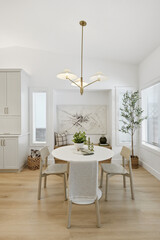 White dining room with a table and chairs, a potted plant