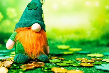 Close-up of St Patrick soft figure standing over green grass with a lot of green and golden coins