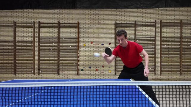 A professional table tennis player makes a backhand shot during practice on a blue table, table tennis