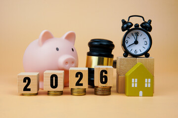 Finance and planning concept for year 2026 with piggy bank, coins, house model, gavel and clock symbolizing savings, investment goals, real estate, taxation and financial decisions for the new year.
