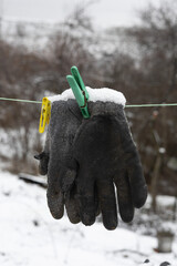 Snow-covered work gloves hanging on a clothespin