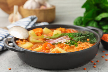 Tasty lentil soup served on grey table, closeup