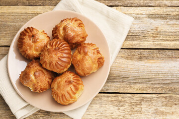 Tasty profiteroles on wooden table, top view. Space for text