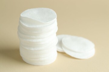 Stack of clean cotton pads on beige background, closeup. Space for text © New Africa