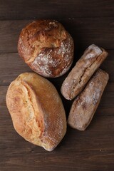 Different types of bread loaves on wooden table, flat lay