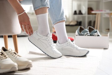 Woman trying on sneakers in shoe store, closeup