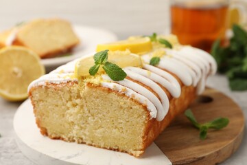 Delicious lemon cake with glaze, fresh fruit slices and mint on table, closeup