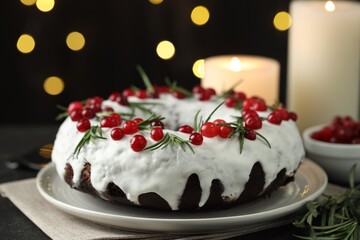 Tasty Christmas cake with cranberries and rosemary on table against blurred lights, closeup