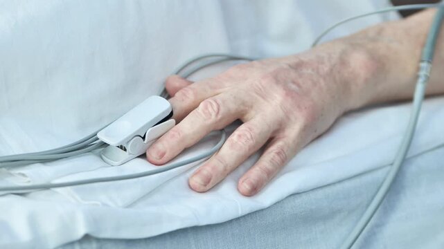 Senior patient hand with pulse oximeter monitoring vital signs in hospital