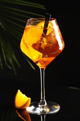 Refreshing spritzer cocktail and orange slice on black table