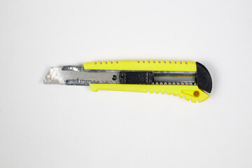 Old, broken construction knife with a yellow handle isolated on white background