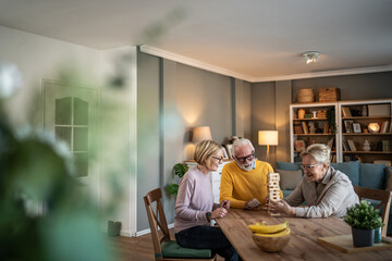 Seniors friends playing jenga board game at home