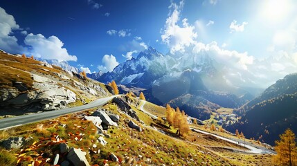 Winding mountain road ascends towards snow-capped peaks under a bright sun