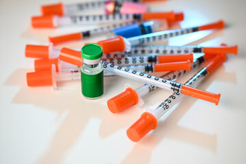 Close up of Pile of Single Use Syringes with Orange Safety Tips and Glass Vials